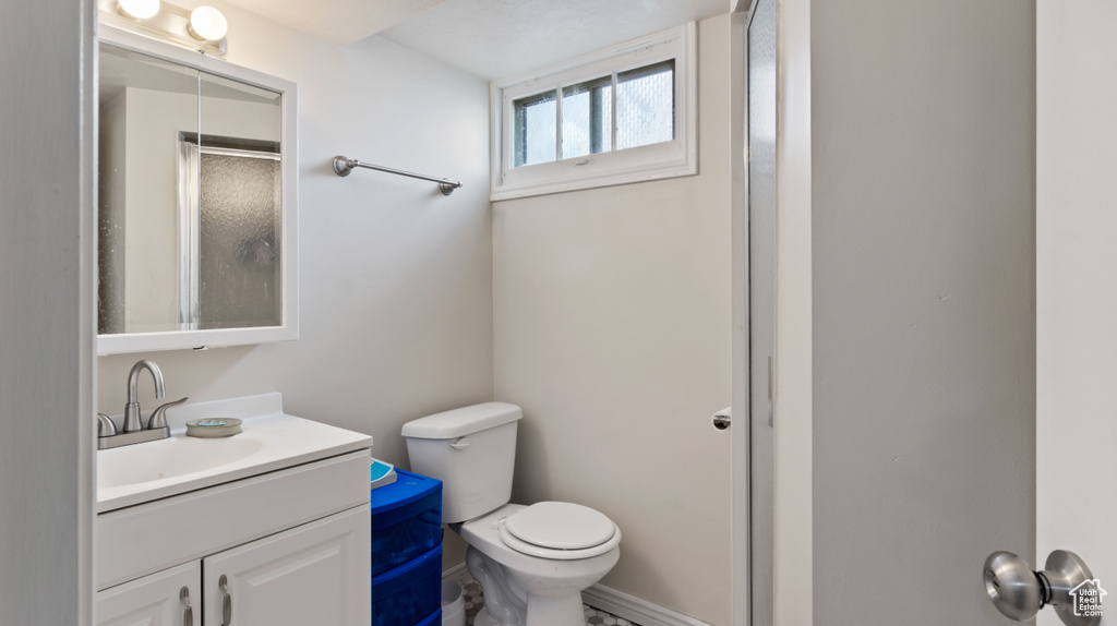 Full bathroom with vanity, a shower with door, and toilet