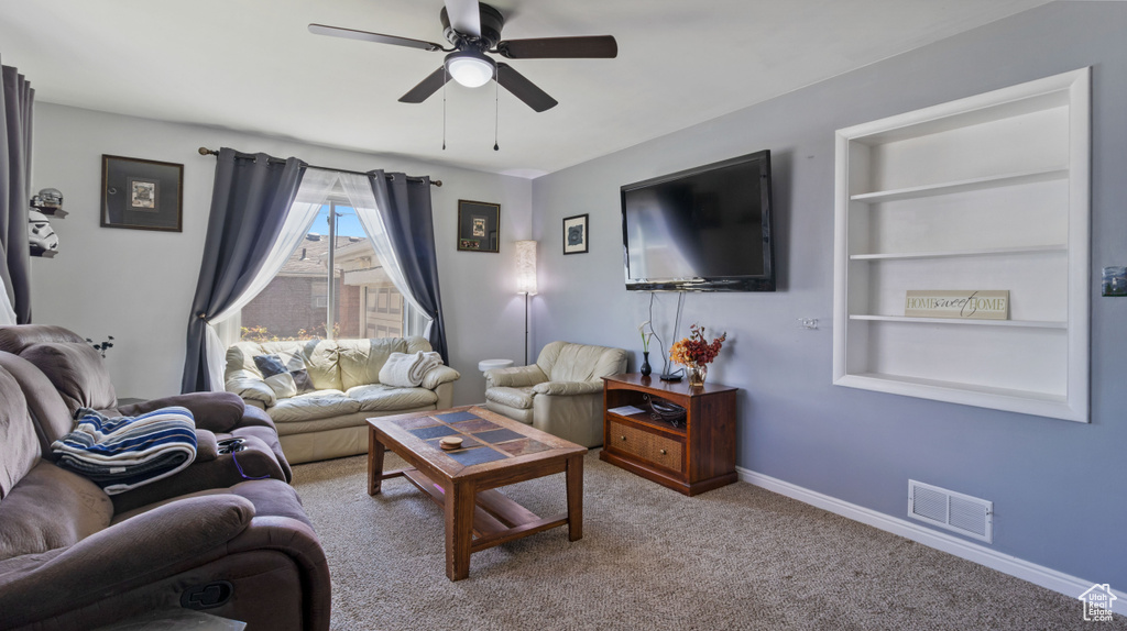 Living area featuring ceiling fan, visible vents, built in features, baseboards, and carpet