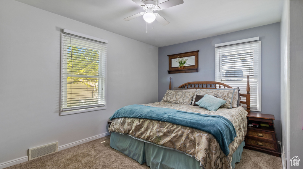 Bedroom with baseboards, carpet, a ceiling fan, and visible vents