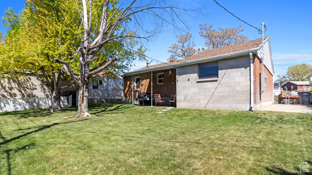 Rear view of property featuring a lawn, fence, and roof with shingles