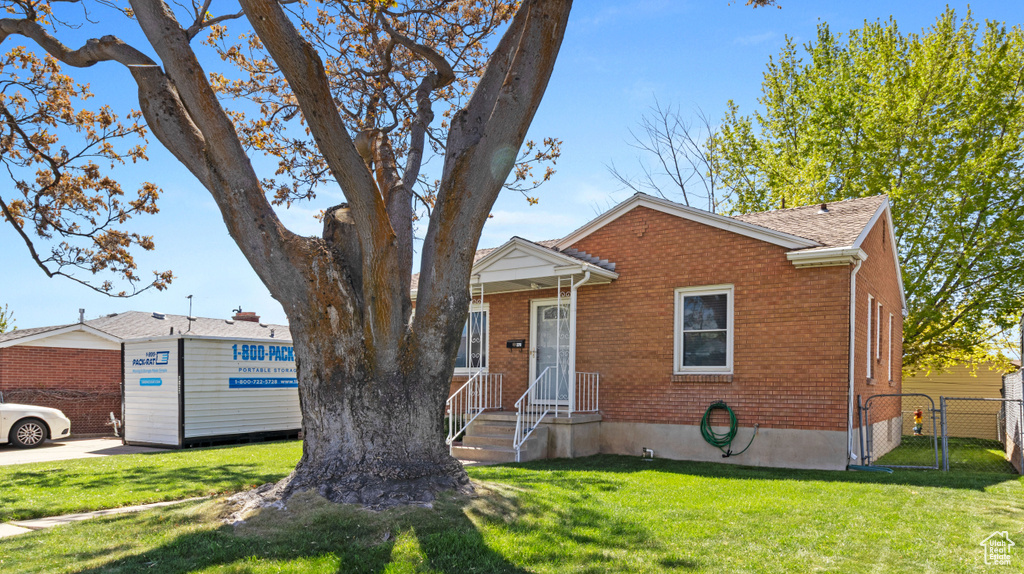 Bungalow with brick siding, a gate, fence, and a front yard