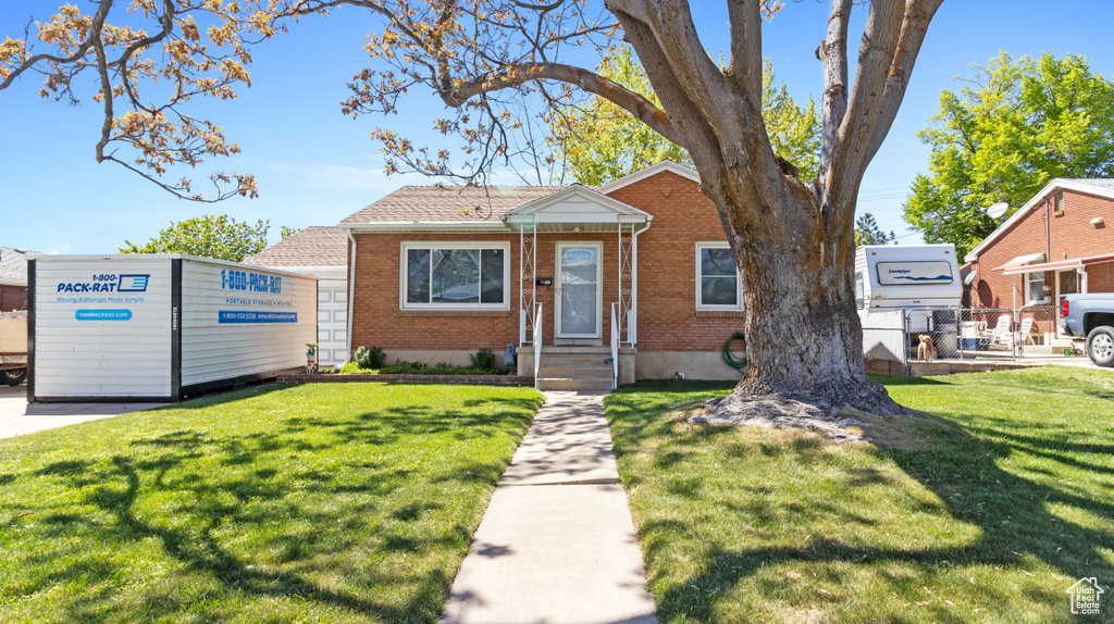 Bungalow-style home featuring brick siding, fence, and a front lawn