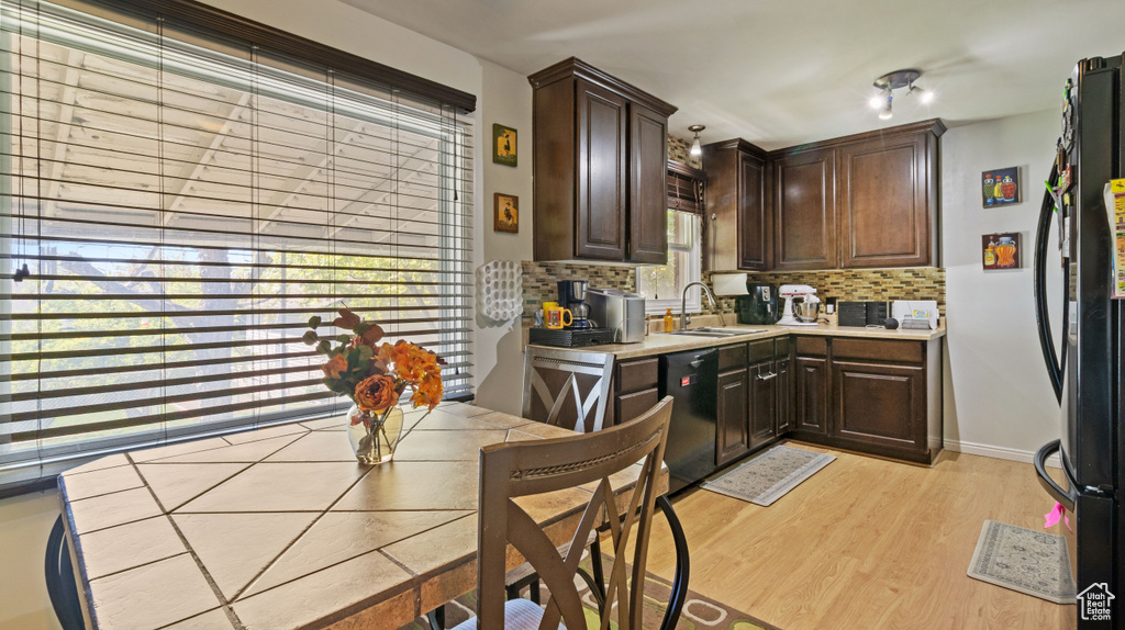 Kitchen with backsplash, dark brown cabinets, and black appliances