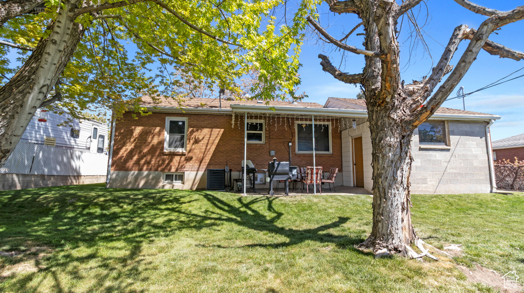 Rear view of property with a yard, a patio, and brick siding