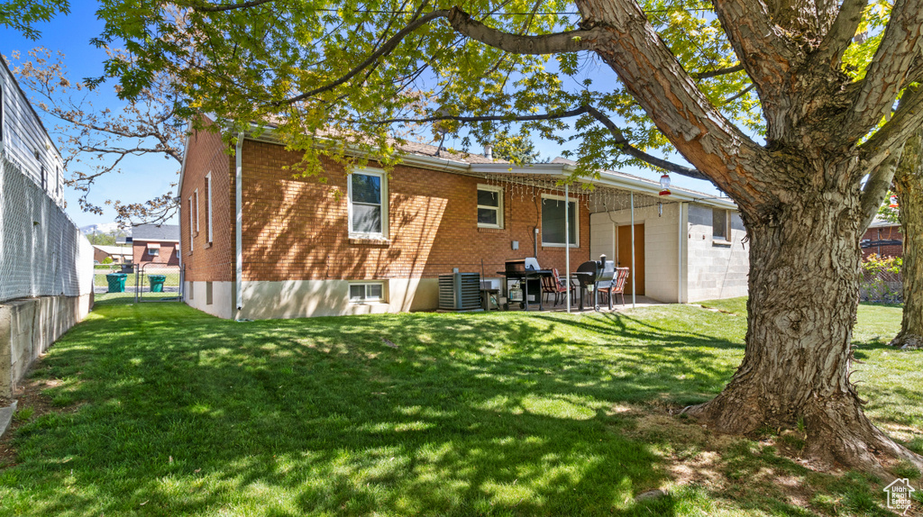 Rear view of house featuring a lawn, brick siding, and a patio area