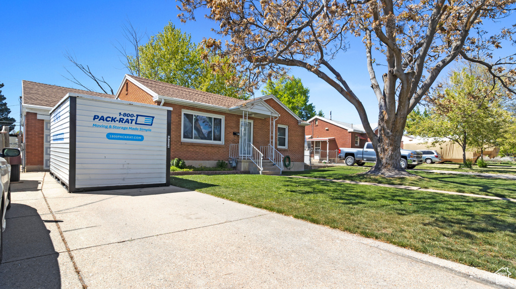 View of front of home featuring brick siding, a front lawn, roof with shingles, and concrete driveway