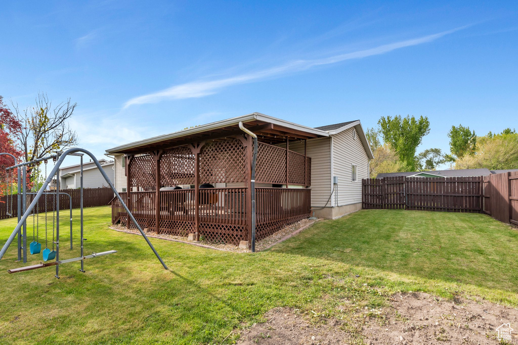 Rear view of house featuring a lawn, a fenced backyard, and a playground