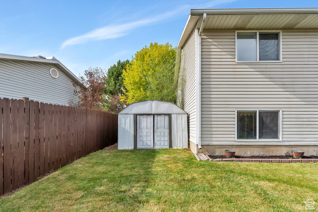 Exterior space featuring a yard, an outdoor structure, fence, and a shed