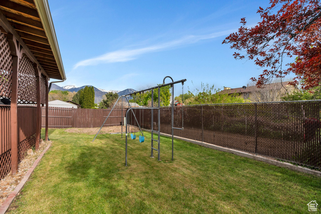 View of yard with a fenced backyard, a playground, and a mountain view