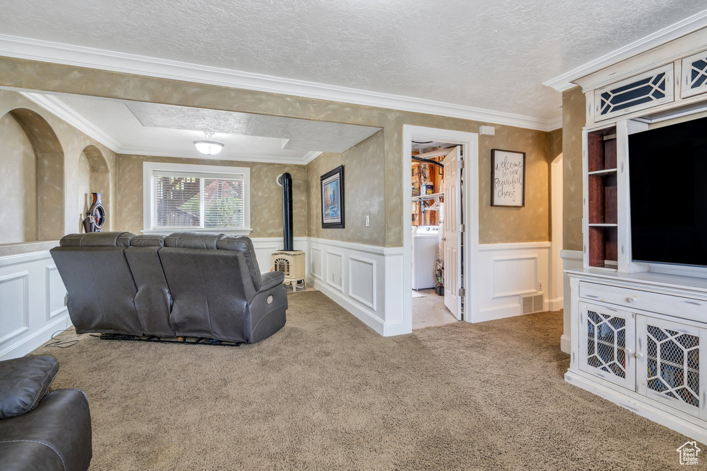 Carpeted living area with a wood stove, washer / clothes dryer, a decorative wall, and a wainscoted wall