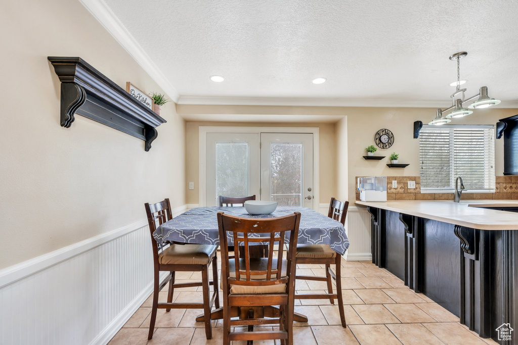 Dining space featuring crown molding, light tile patterned floors, a textured ceiling, and a healthy amount of sunlight