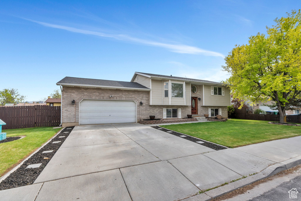 Split foyer home featuring fence, an attached garage, and brick siding
