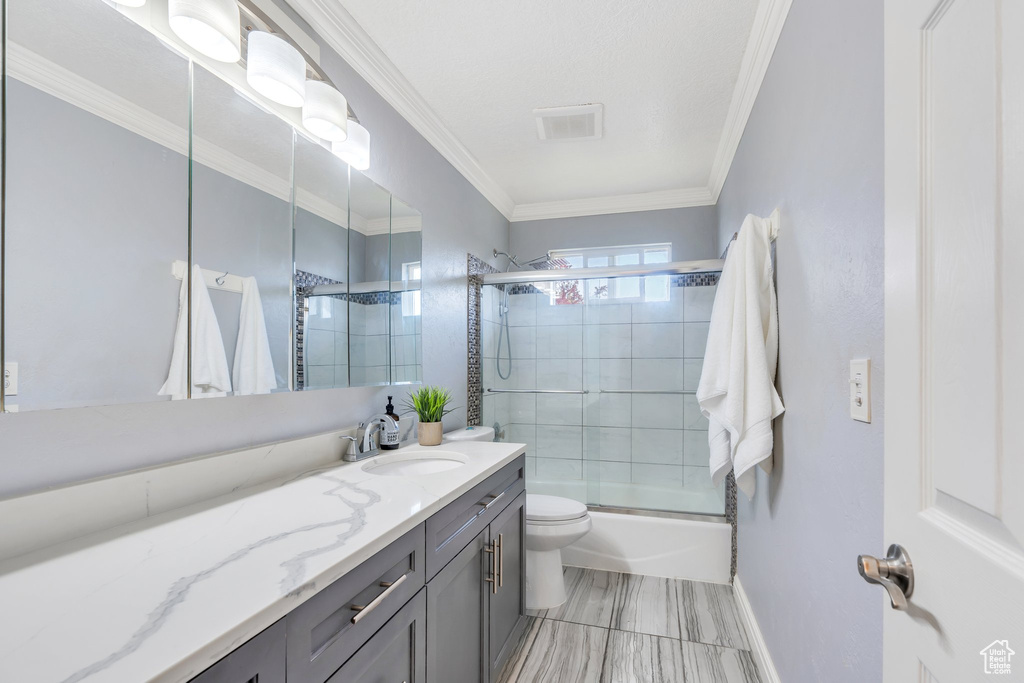 Bathroom featuring crown molding, vanity, toilet, enclosed tub / shower combo, and baseboards