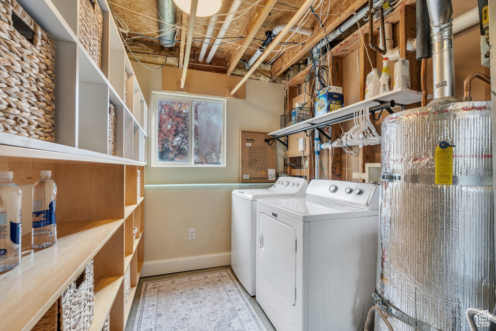Clothes washing area featuring washing machine and clothes dryer, baseboards, and laundry area