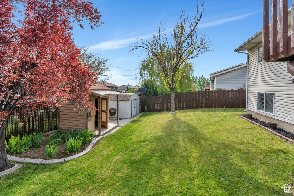 View of yard featuring a fenced backyard, a shed, and an outbuilding