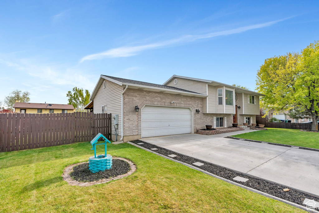 View of front of house with concrete driveway, brick siding, fence, and a garage