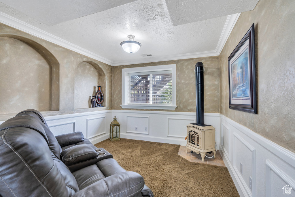Sitting room with crown molding, a textured ceiling, carpet floors, and a wood stove