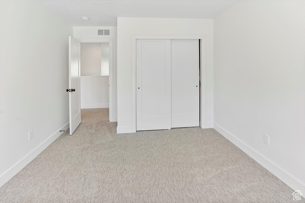 Unfurnished bedroom featuring baseboards, a closet, carpet flooring, and visible vents