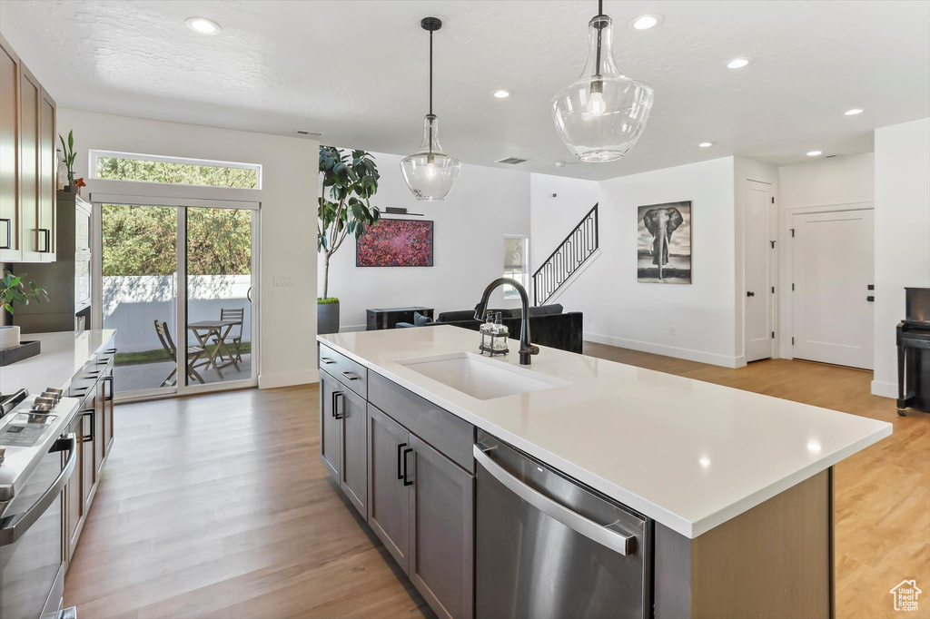Kitchen with stainless steel dishwasher, a sink, stove, and light countertops