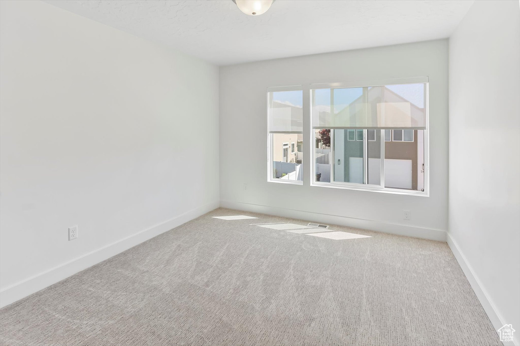Empty room featuring baseboards, carpet, and visible vents
