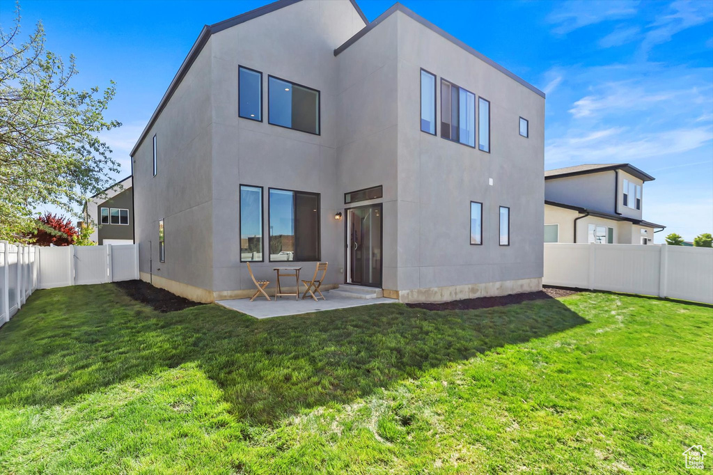 Rear view of house featuring a patio area, stucco siding, and a yard