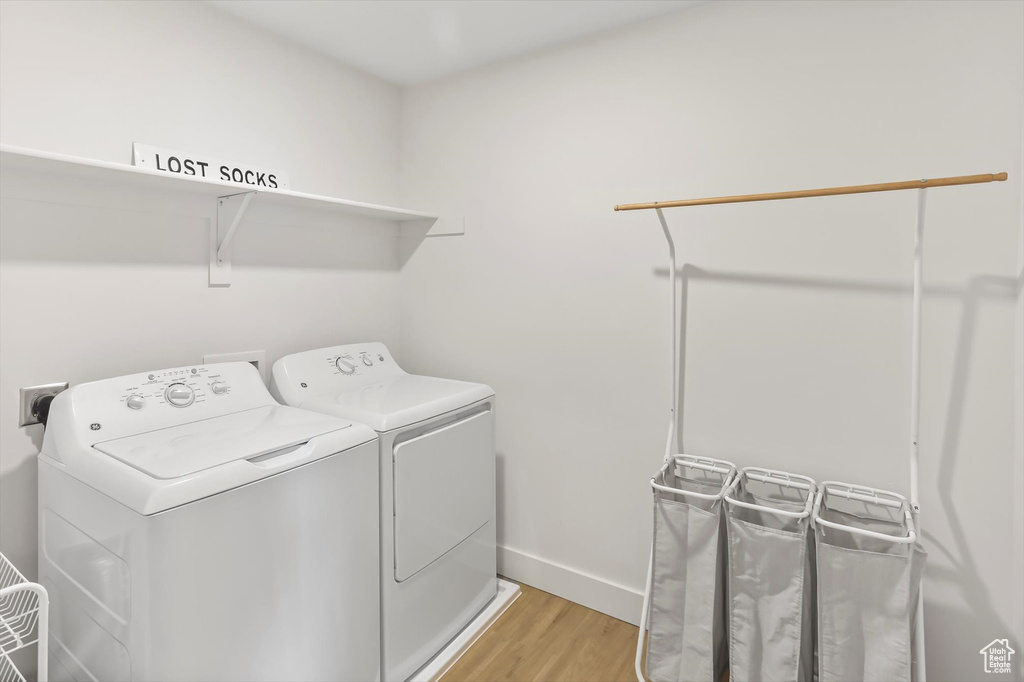 Clothes washing area with baseboards, laundry area, light wood-style flooring, and washer and clothes dryer