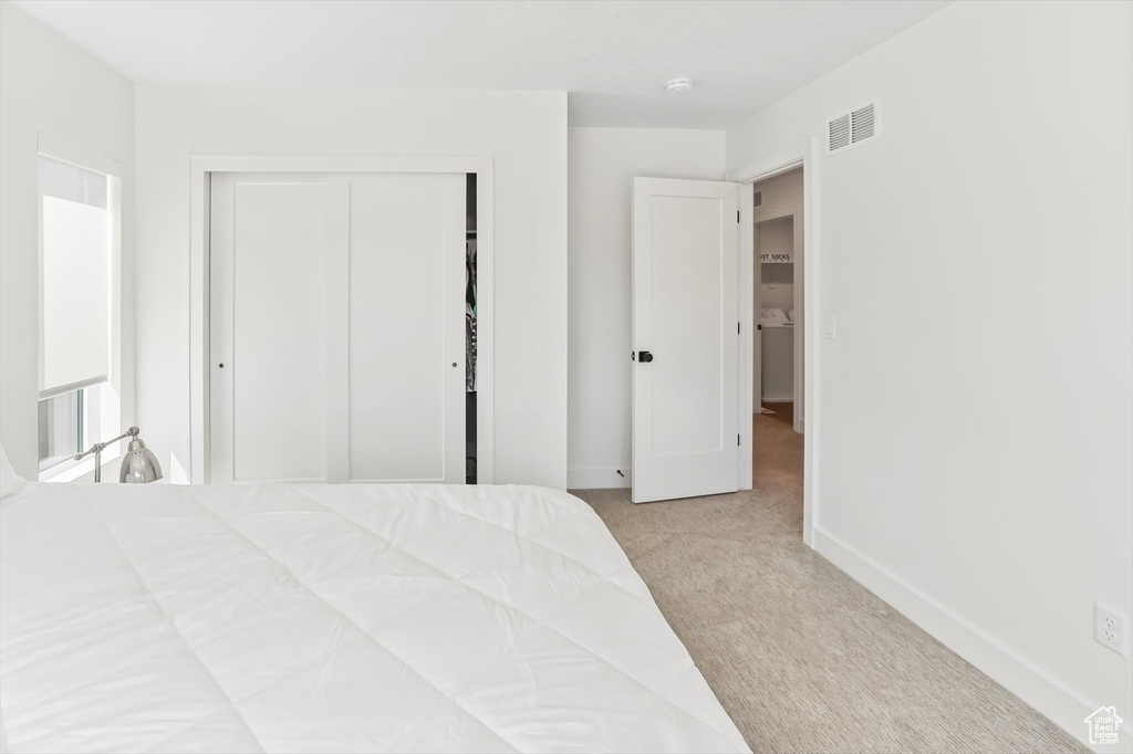 Carpeted bedroom featuring visible vents, baseboards, and a closet
