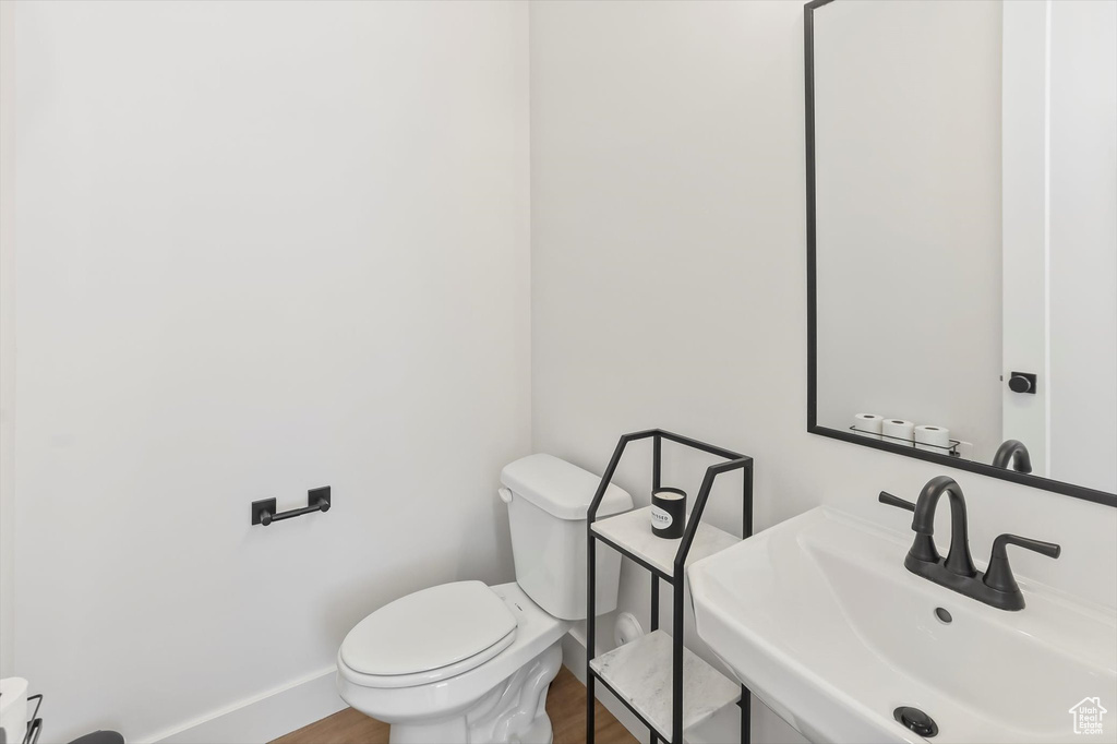 Bathroom with a sink, baseboards, toilet, and wood finished floors