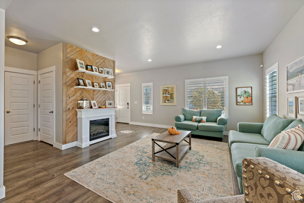 Living area with dark wood-type flooring, recessed lighting, baseboards, and a glass covered fireplace