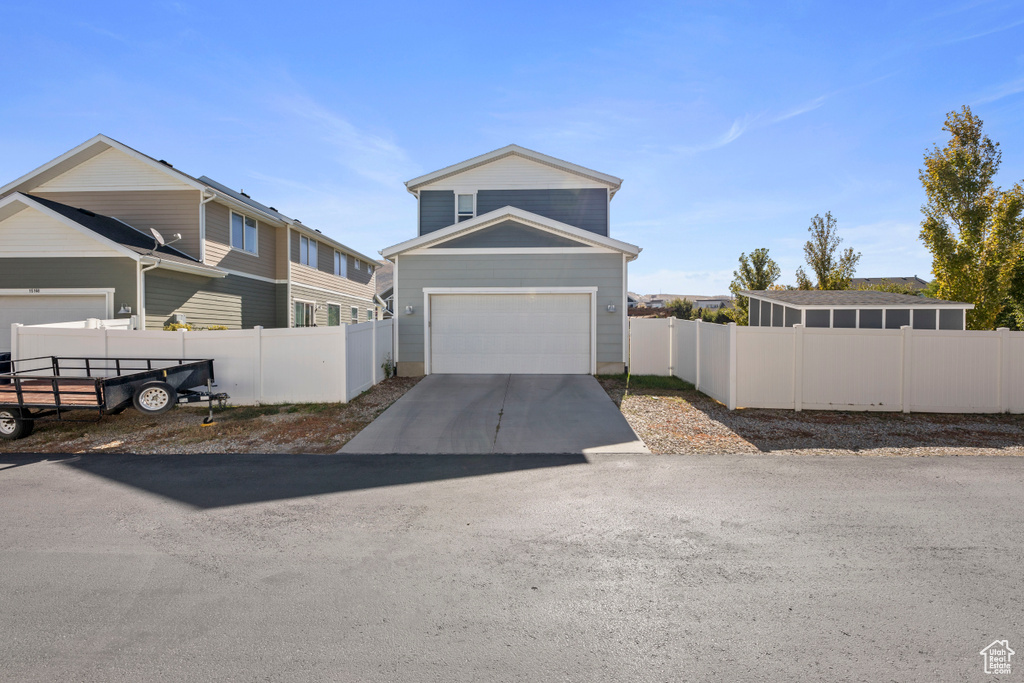 View of front of house with fence, driveway, and a garage