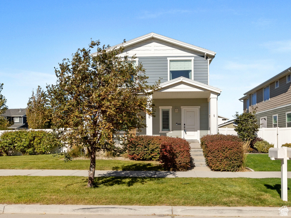 View of front of house featuring fence and a front lawn