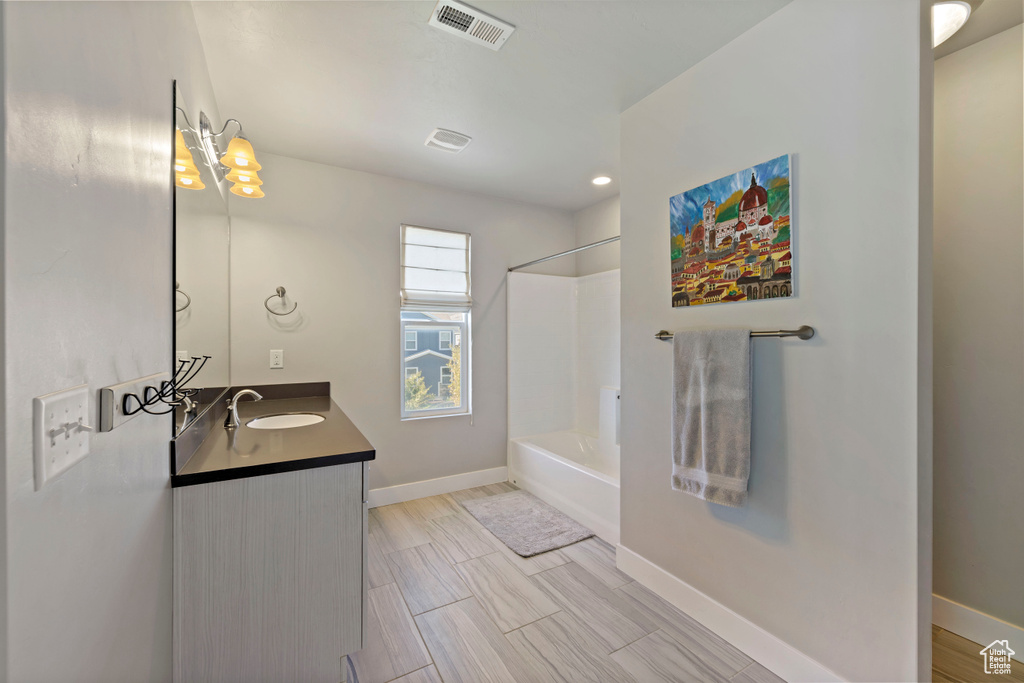 Bathroom with shower / bathtub combination, baseboards, visible vents, and vanity