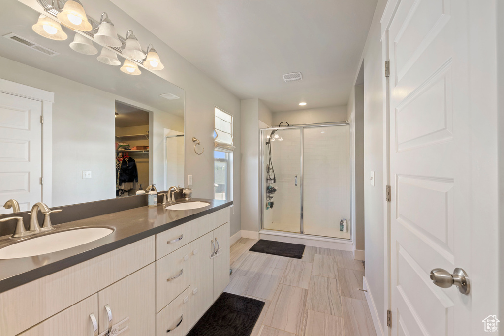Bathroom featuring visible vents, a sink, a walk in closet, and a shower stall
