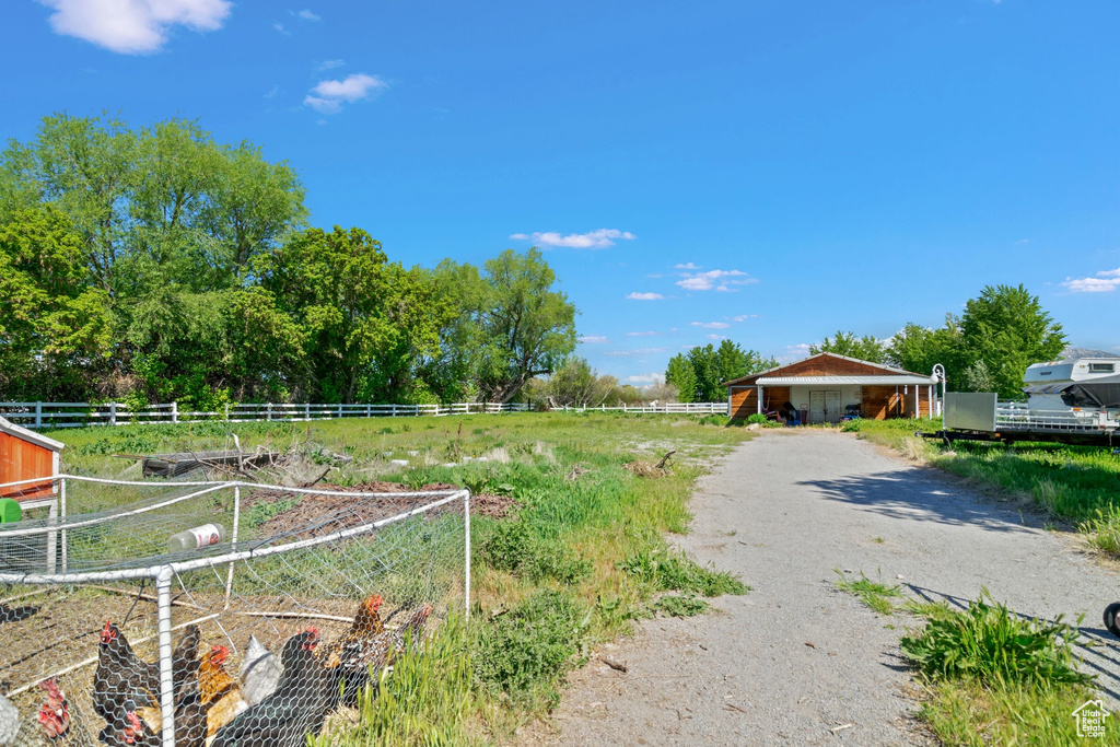 View of yard featuring fence, dirt driveway, and a rural view