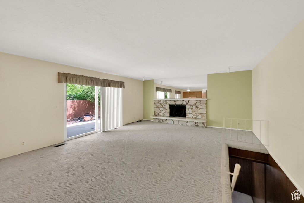 Unfurnished living room featuring carpet floors, a fireplace, and visible vents
