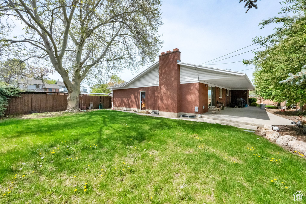 Rear view of property with a patio, fence, a yard, and a chimney