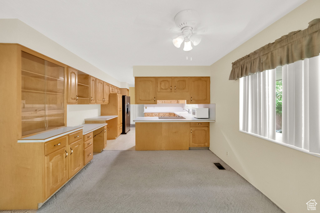 Kitchen featuring open shelves, ceiling fan, light carpet, light countertops, and a peninsula