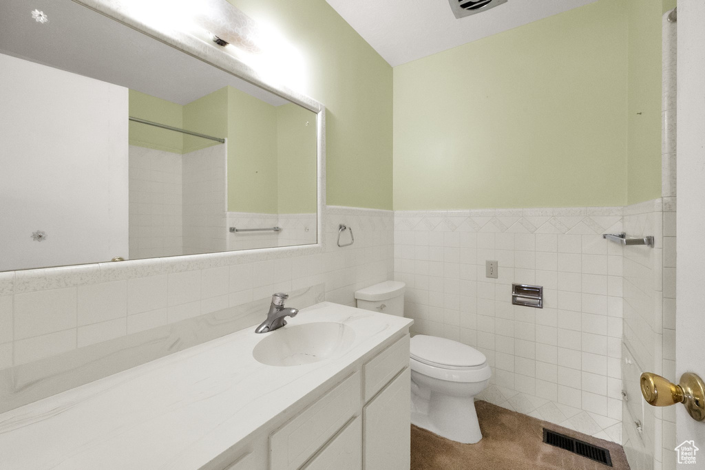 Full bathroom with wainscoting, vanity, toilet, a shower, and visible vents