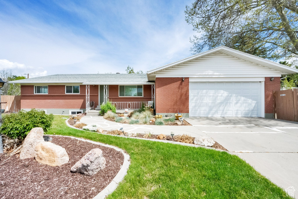 Ranch-style house with brick siding, a garage, a porch, a front yard, and concrete driveway
