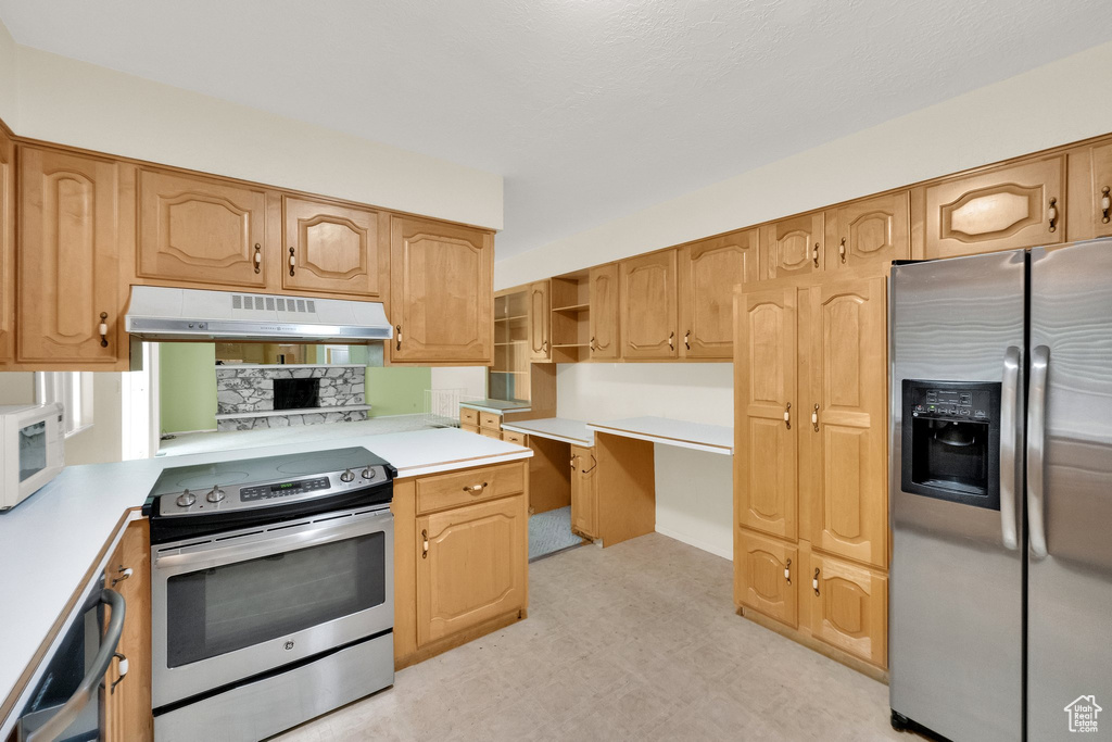 Kitchen with light countertops, light floors, appliances with stainless steel finishes, and under cabinet range hood