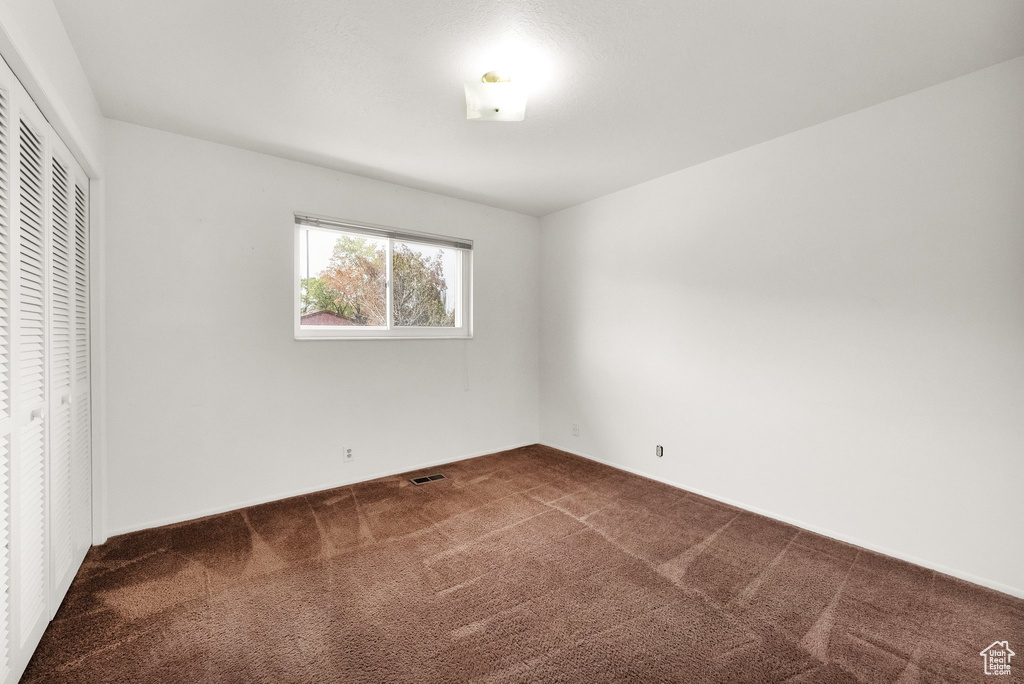 Unfurnished bedroom featuring a closet, carpet flooring, and visible vents
