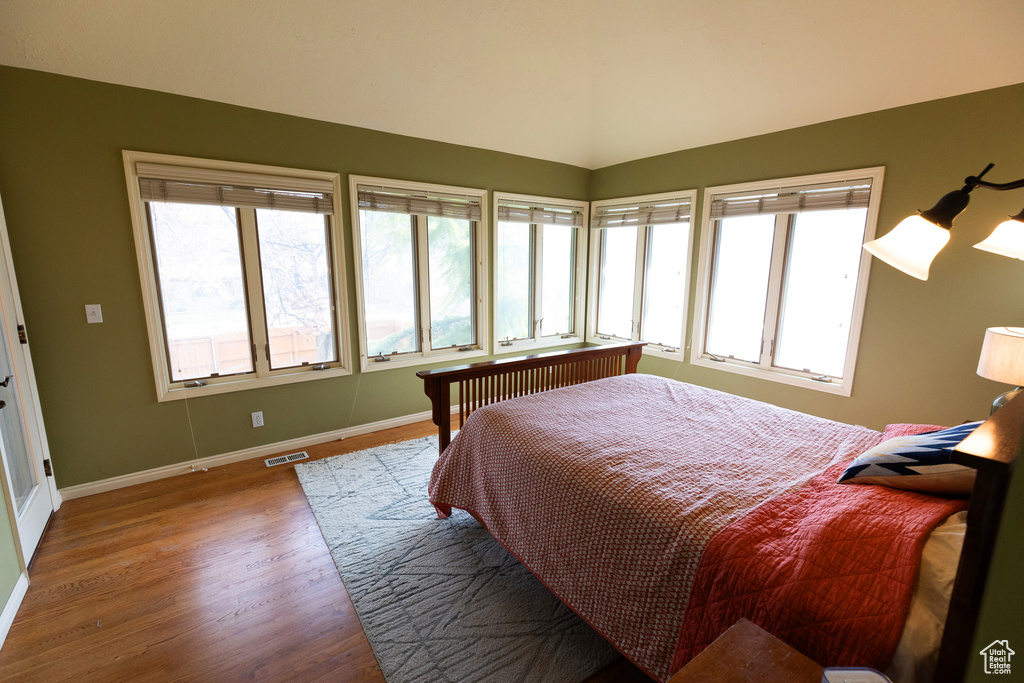 Bedroom with visible vents, baseboards, lofted ceiling, and wood finished floors