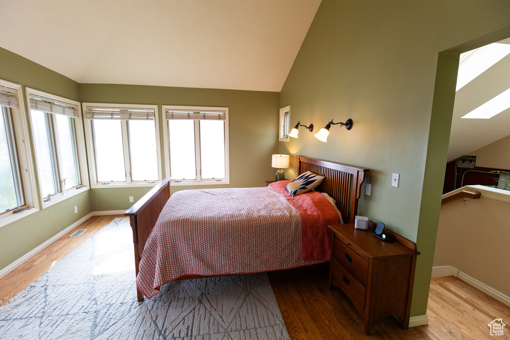 Bedroom with wood finished floors and vaulted ceiling with skylight