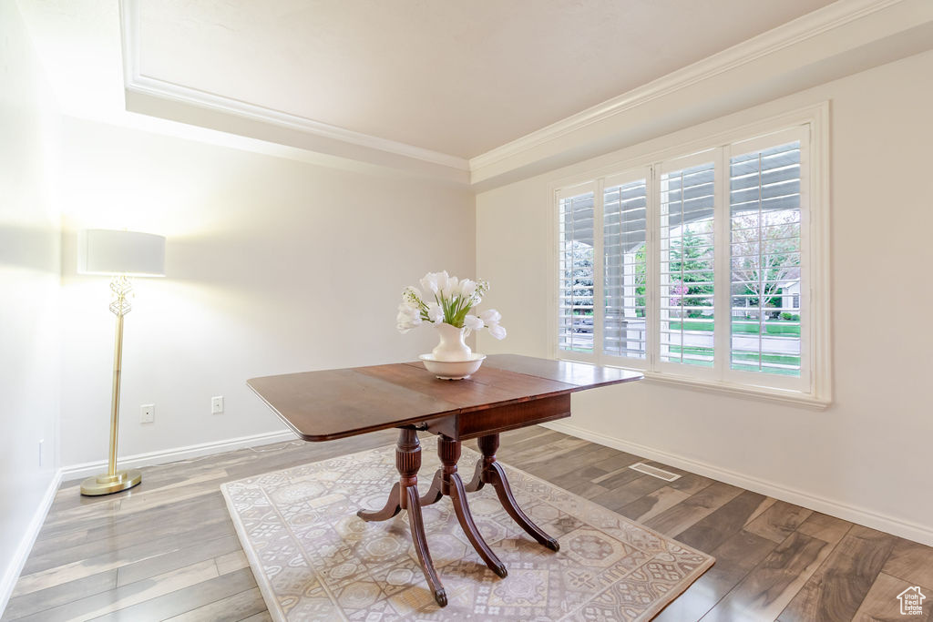 Dining area with crown molding, a tray ceiling, wood finished floors, and baseboards