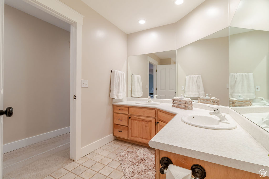 Bathroom with tile patterned floors, baseboards, double vanity, and a sink