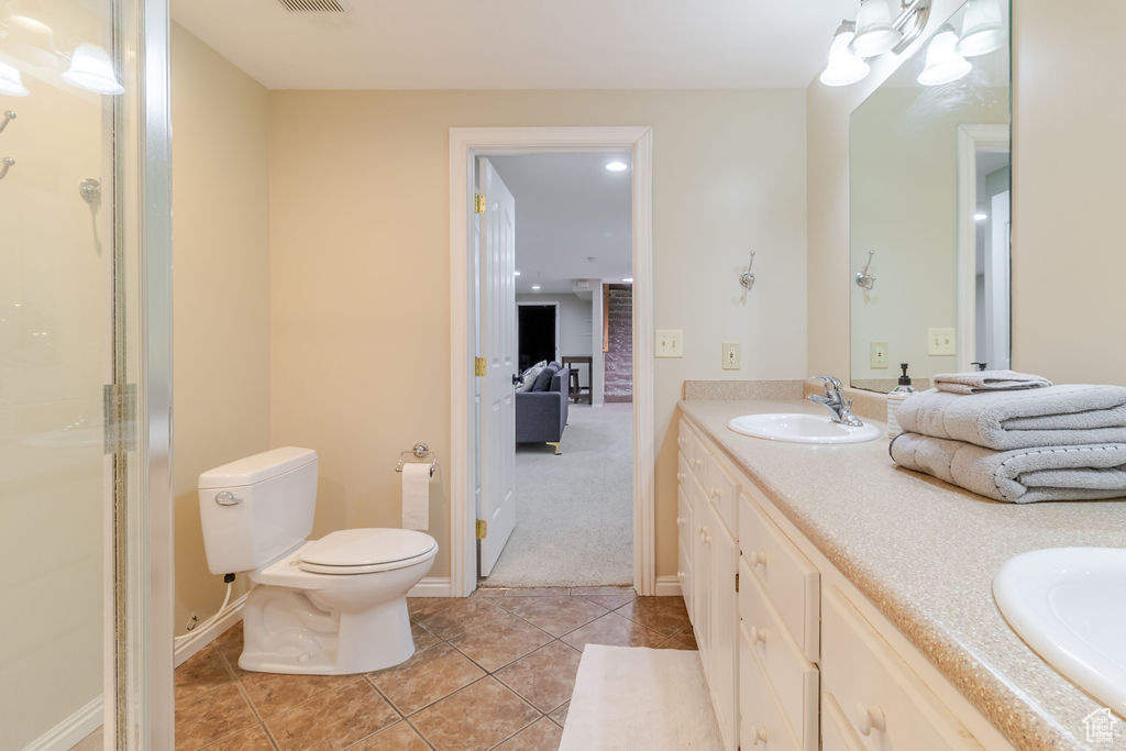 Bathroom featuring a sink, double vanity, baseboards, toilet, and tile patterned flooring