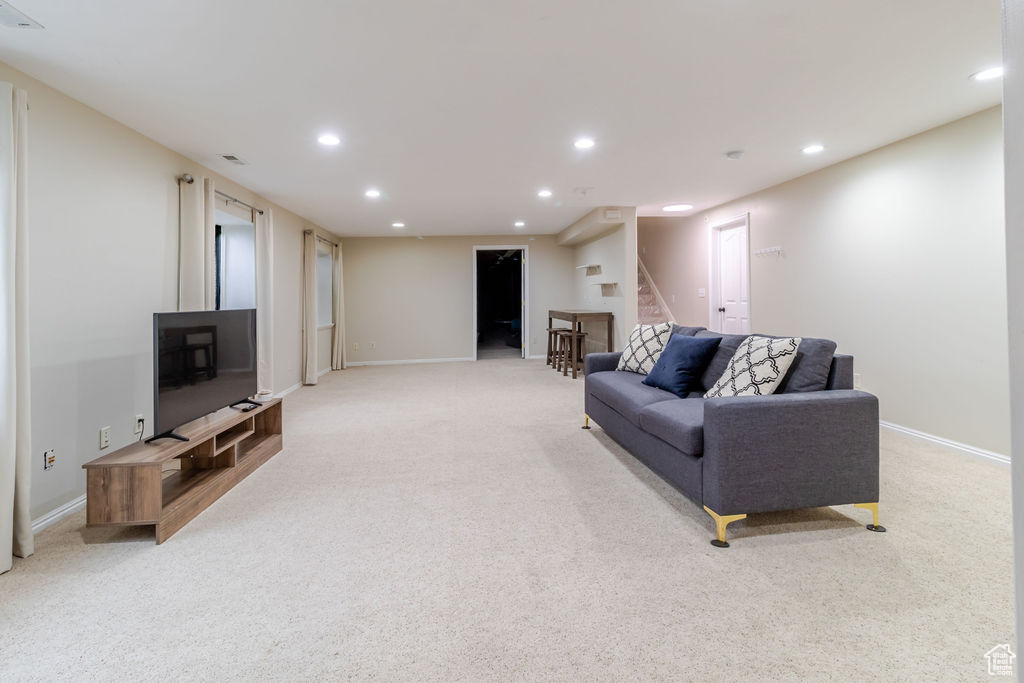 Living area with recessed lighting, stairs, and light colored carpet