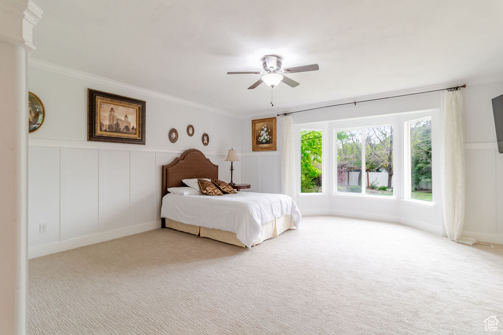 Bedroom with ornamental molding, carpet flooring, and a decorative wall