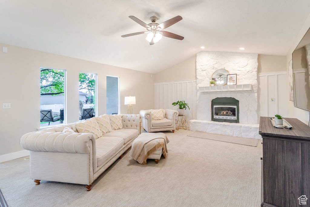 Living area with ceiling fan, vaulted ceiling, and a fireplace