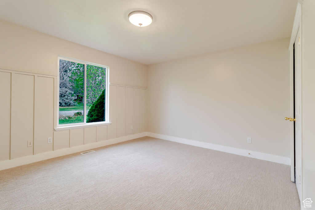 Spare room featuring visible vents, baseboards, wainscoting, and light carpet